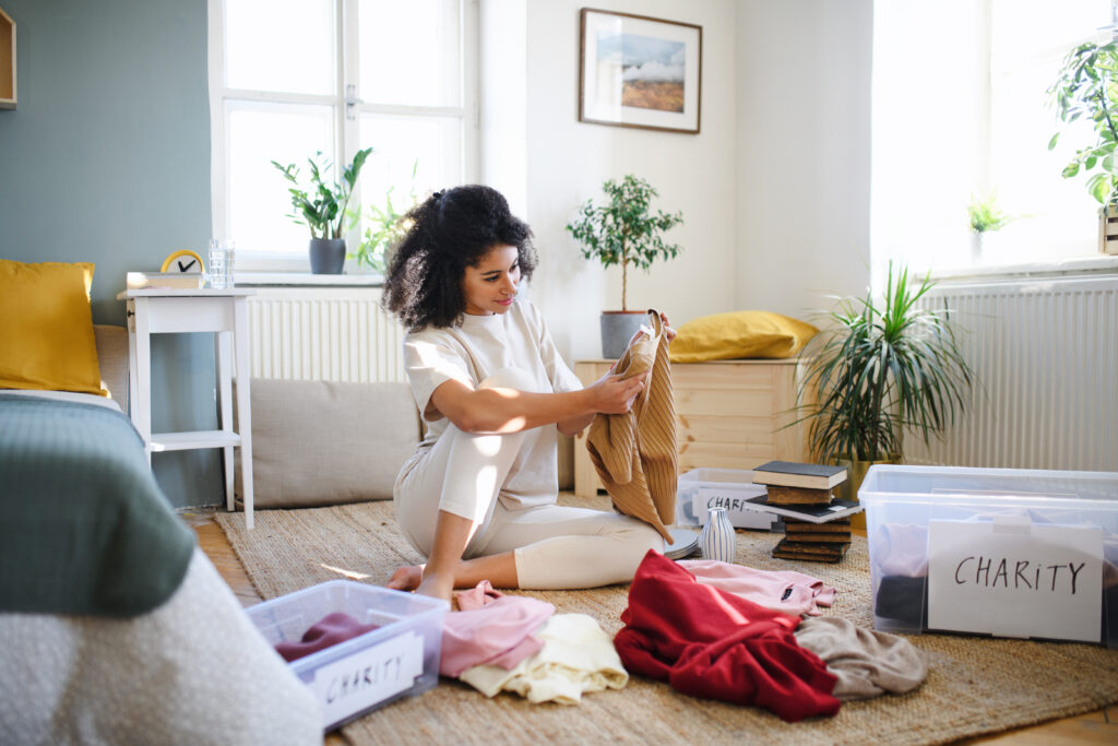 woman sitting down decluttering her home by going through items and boxes