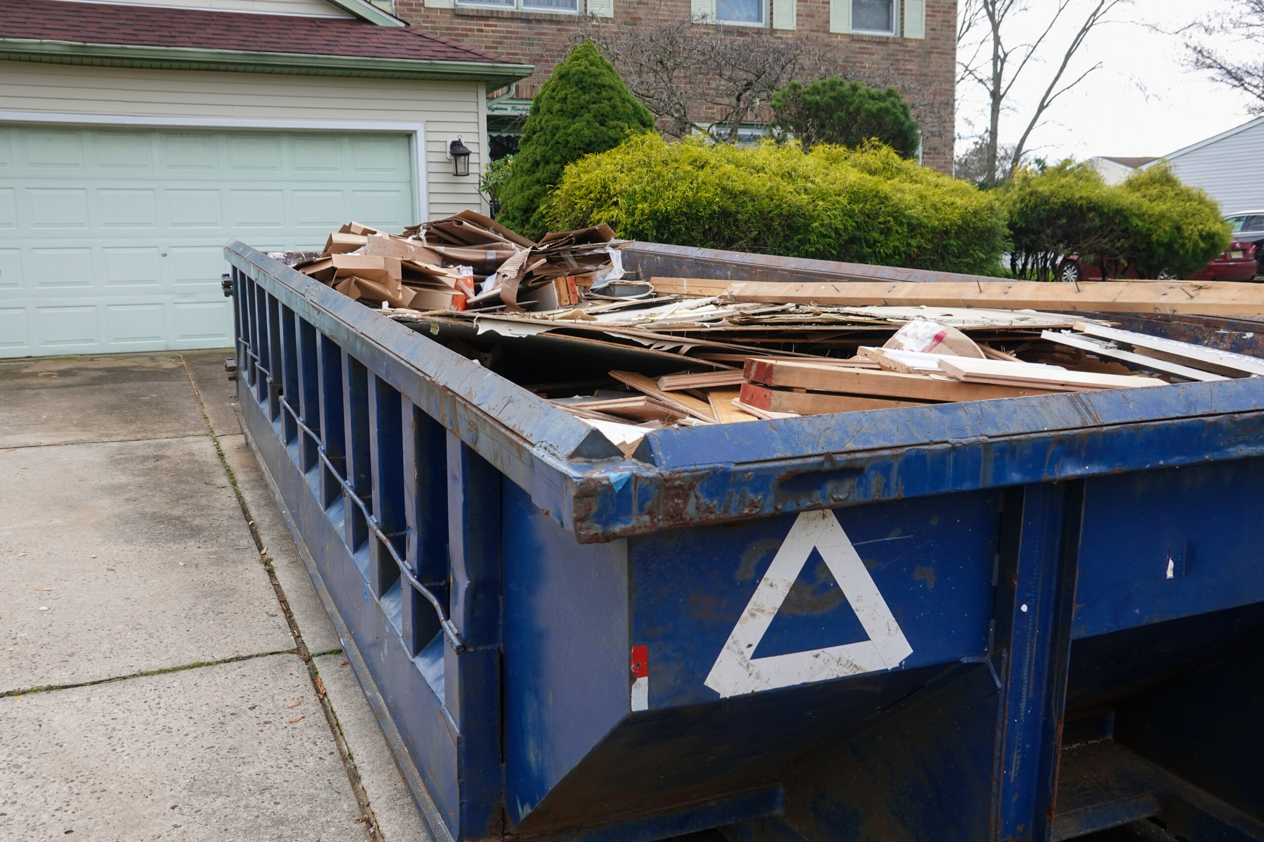 blue dumpster at home loaded with trash and wood from home